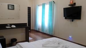 Whistling Wind Resorts by StayApart في لاتاغري: غرفة نوم بسرير وتلفزيون بشاشة مسطحة