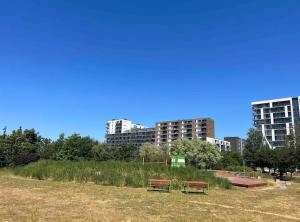 two benches in a field with buildings in the background at Fully equipped apartment, 15 min to Downtown in Copenhagen