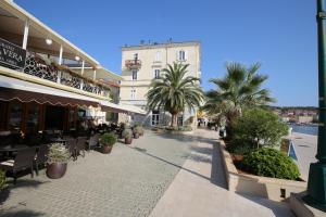 a street with tables and chairs and palm trees at Apartments and Rooms Jospino in Mali Lošinj