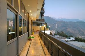 a balcony of a building with a view of a mountain at Hotel Varuni- On Mall Road, Mcleod Ganj, Dharamshala in Dharamshala