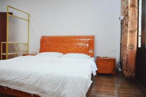 a bed with a wooden headboard in a bedroom at Banyan Bay Homestay, Meizhou Island in Meizhou