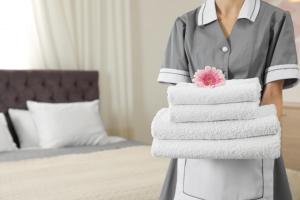 uma mulher segurando uma pilha de toalhas em um quarto de hotel em Crowne Plaza Perth, an IHG Hotel em Perth