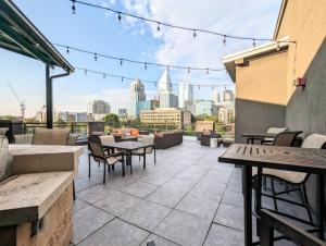 a rooftop patio with tables and chairs and a city skyline at League Flats South End at South Blvd in Charlotte