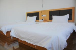 two beds in a hotel room with white sheets at Banyan Bay Homestay, Meizhou Island in Meizhou