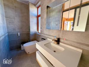 W łazience znajduje się umywalka, toaleta i lustro. w obiekcie Lijiang Shitian B&B w mieście Lijiang