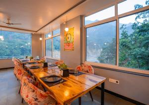 瑞诗凯诗Moustache Rishikesh Riverside Resort的用餐室设有长木桌和窗户。