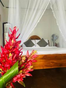 um quarto com uma cama com flores vermelhas em Hidden Gem Inn em Ella
