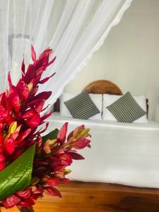 uma cama com um dossel branco com flores vermelhas em Hidden Gem Inn em Ella