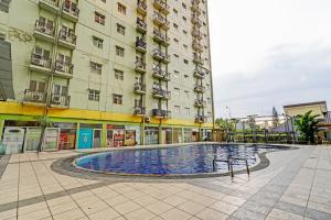 een groot gebouw met een zwembad ervoor bij OYO 93426 Metro Suites Apartment By Goodvibes in Bandung