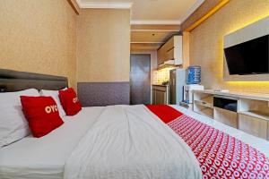 een slaapkamer met een groot bed met rode kussens bij OYO 93426 Metro Suites Apartment By Goodvibes in Bandung