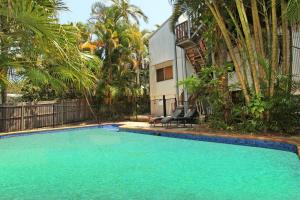a swimming pool in front of a building with palm trees at Mayfield 23 in Alexandra Headland