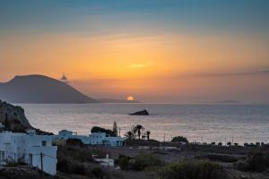 a sunset over the ocean with white buildings and a beach at Arkasa Palace in Arkasa