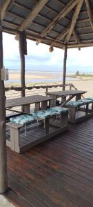 una terraza de madera con bancos en la playa en Barra house, en Inhambane