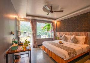 瑞诗凯诗Moustache Rishikesh Riverside Resort的带一张大床和一扇窗户的卧室