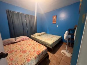 2 camas en una habitación con paredes azules en Las Casitas de Playa Ne gra, en Puerto Viejo