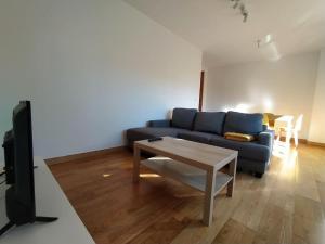 a living room with a blue couch and a table at Apartamento en Astillero con plaza de aparcamiento in El Astillero