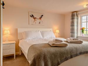 ein Schlafzimmer mit einem Bett mit zwei Handtüchern darauf in der Unterkunft 3 Bed in Reedham 47835 in Haddiscoe