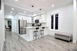 cocina blanca con barra y sofá en Luxury home by Tim Hortons Field, en Hamilton
