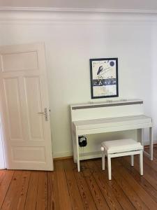 a white piano with a bench next to a door at Wohlfühlen in Winterhude in Hamburg