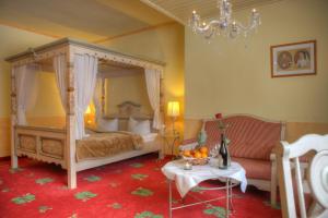 a bedroom with a canopy bed and a table at Romantik Hotel Zum Lindengarten in Kurort Jonsdorf