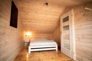 a small bedroom with a bed in a wooden room at Mazury w Pigułce- domek z sauną i balią, Woszczele in Ełk
