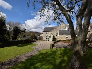 a large stone house with a tree in the foreground at 3 Bed in Harbottle 61257 in Harbottle