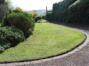 ウーラーにある2 bed property in Wooler Northumberland CN226の緑の芝生と茂みのある庭園