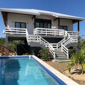 a house with a swimming pool in front of a house at La Vida Belize - Casa in Riversdale