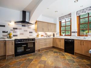 a large kitchen with wooden cabinets and black appliances at 5 Bed in Bishops Frome 75602 in Bishops Frome