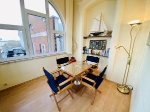 una sala da pranzo con tavolo, sedie e finestra di Promenadenblick/Captains-Suite a Warnemünde