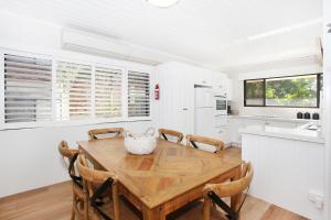 a white kitchen with a wooden table and chairs at Windmill 3 in Mooloolaba