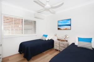 a bedroom with two beds and a ceiling fan at Windmill 3 in Mooloolaba