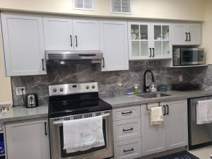 a kitchen with white cabinets and a stove top oven at 3 BR House in Toronto Downtown in Toronto