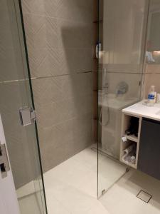 een douche met een glazen deur naast een wastafel bij Luxury New Studio with Pool & Gym Access, 5 min from Gardens Metro in Dubai