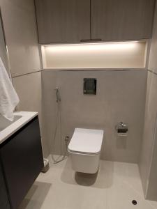 een badkamer met een wit toilet en een licht bij Luxury New Studio with Pool & Gym Access, 5 min from Gardens Metro in Dubai