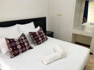 un letto bianco con cuscini e un asciugamano. di Sombedu guest suite a Margate