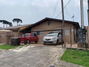 zwei Autos neben einem Gebäude mit einem Zaun in der Unterkunft Studio Residencial Curitiba Apartament in Curitiba