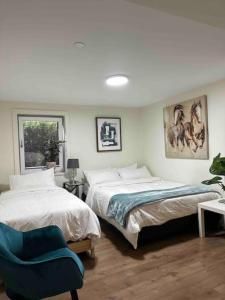 sypialnia z 2 łóżkami i niebieskim krzesłem w obiekcie Patio Suite at The Inn On The Drive w mieście Vancouver