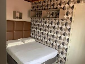 um pequeno quarto com uma cama e uma parede em azulejo em Studio Residencial Curitiba Apartament em Curitiba