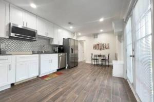 a large kitchen with white cabinets and a wooden floor at The Beach Pad - Your Private Oasis with a Cool Beachy Vibe in Manassas Park