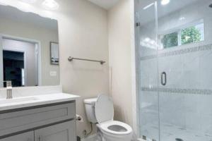 a bathroom with a toilet and a glass shower at The Beach Pad - Your Private Oasis with a Cool Beachy Vibe in Manassas Park