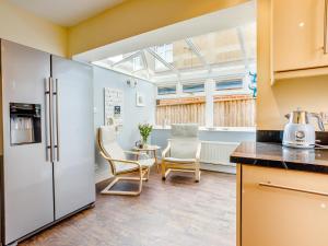 a kitchen with a refrigerator and chairs and a table at 3 Bed in Sidmouth 78021 in Sidmouth