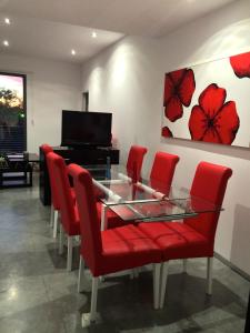 uma sala de jantar com cadeiras vermelhas, uma mesa de vidro e um piano em Apartamentos Turísticos Córdoba Califal em Córdoba