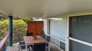 a porch with a wooden table and chairs on a balcony at Island View 1 in Coffin Bay