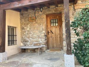 a stone house with a wooden door and a bench at El Alamo. Azagalla Rural in Casas del Abad