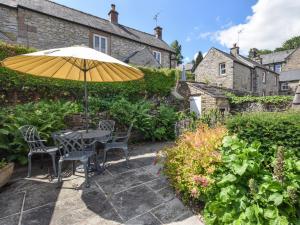 a table and chairs under an umbrella in a garden at 2 Bed in Winster 81043 in Winster