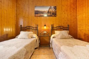 two beds in a room with wooden walls at Casa Doña Margarita in Tuineje