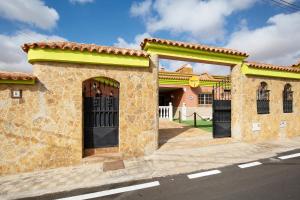 a brick building with black doors on a street at Casa Doña Margarita in Tuineje