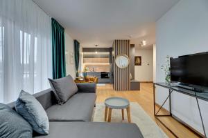 a living room with a couch and a tv at Downtown Apartments Riverside Nadmotławie - Sauna, Gym & Parking in Gdańsk