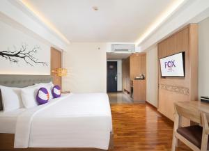 1 dormitorio con 1 cama blanca grande y escritorio en FOX Hotel Jimbaran Beach, en Jimbaran